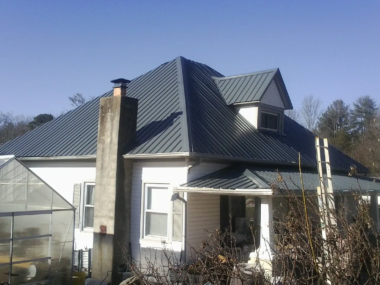 Dark blue standing seam metal roof on a white farmhouse with dormer — Slate & Tile Roof Repair by Roofing Brothers in Fort Monmouth