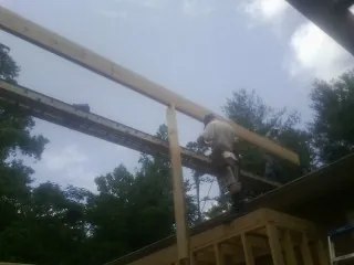 Carpenter setting a ridge beam over a new addition frame in Fort Monmouth