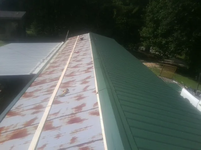 Old rusted panels beside newly installed green metal roofing — Wind Damage Roof Repair by Roofing Brothers in Fort Monmouth