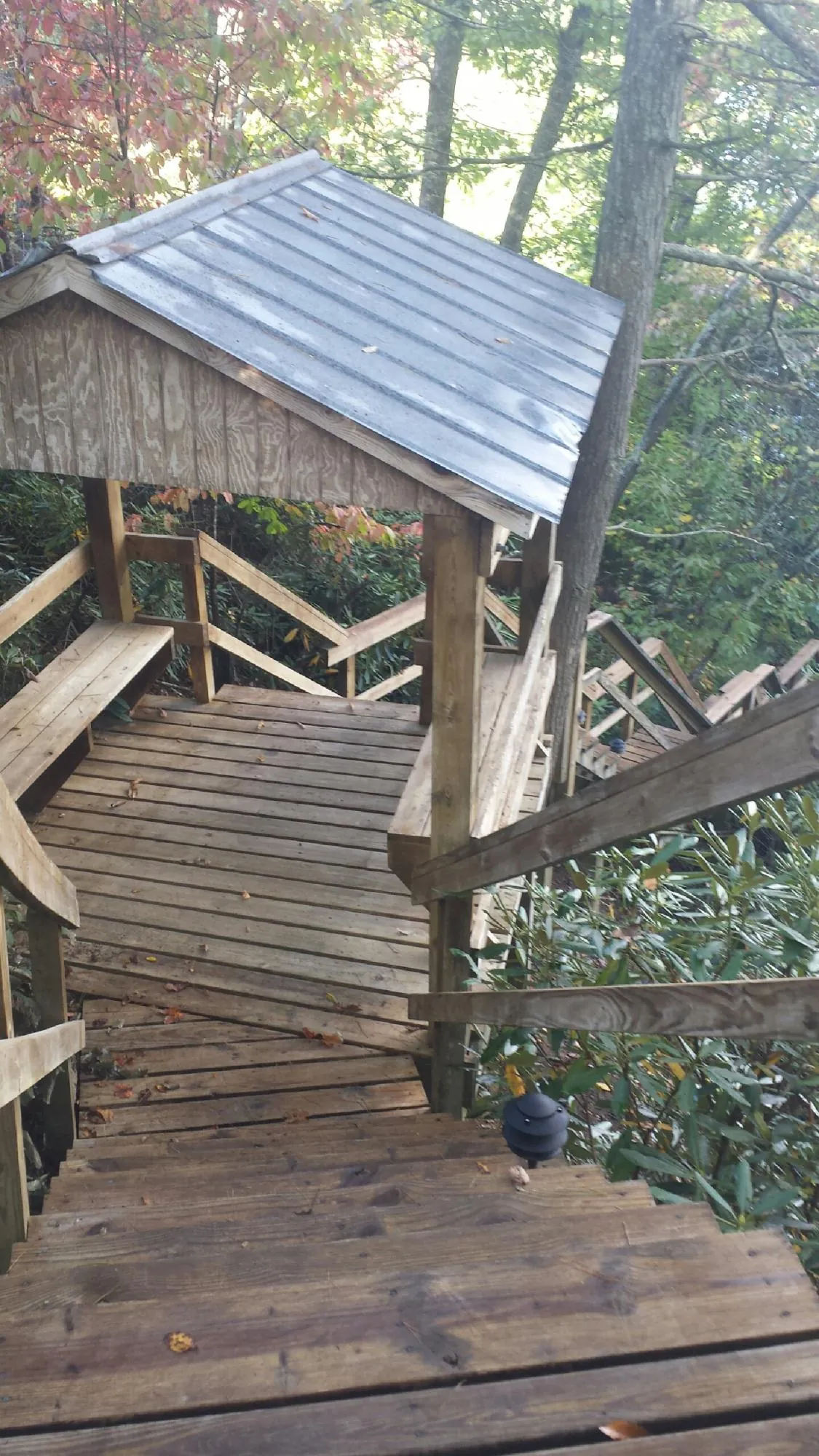 Metal roofed shelter over wooden steps on a wooded walkway — Skylight Repair & Installation work by our crew in Fort Monmouth