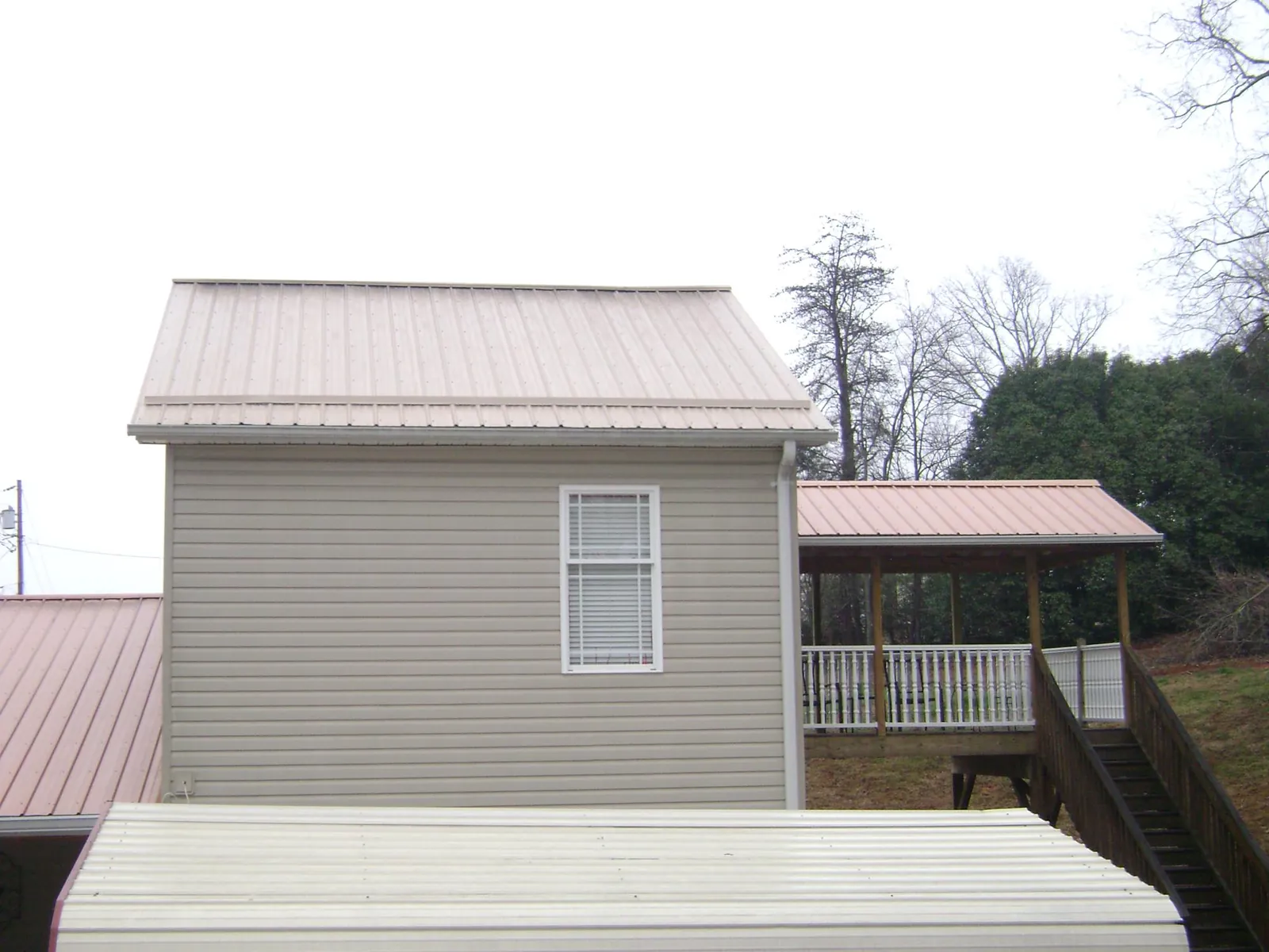 Tan metal roofs on a two story addition and attached porch, from a Roof Replacement job in Fort Monmouth