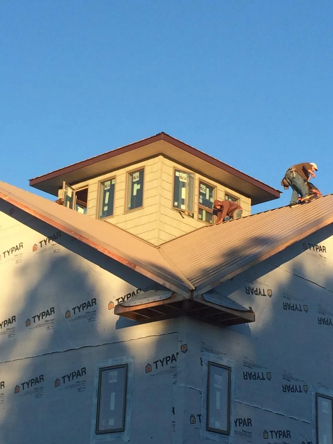 Roofers working around a rooftop cupola on a new metal roof at sunset — Roof Waterproofing in Fort Monmouth by Roofing Brothers